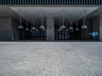 a building with various lamps in front of it on a brick floor and stone pillars