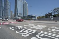 cityscape in the background with tall buildings on either side of the road and cars driving