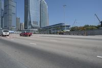 cityscape in the background with tall buildings on either side of the road and cars driving