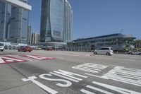 cityscape in the background with tall buildings on either side of the road and cars driving