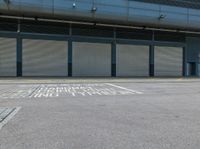 a street with garage doors and some people walking on the side of the road near a building