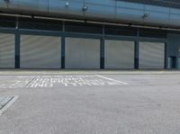 a street with garage doors and some people walking on the side of the road near a building