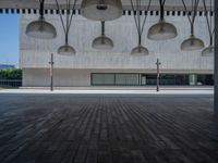 an empty walkway near buildings with several large lights hanging from the ceiling above them in a city