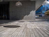 a large concrete building has four floor lamps in it's corner, and a bench on a hard wood plank floor