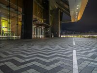 a tiled empty parking lot with buildings and sky in the background on a cold winter night