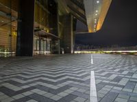 a tiled empty parking lot with buildings and sky in the background on a cold winter night