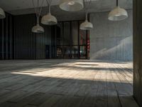 an empty room with wooden floors and multiple hanging lights overhead in the area along the walls