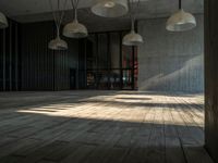 an empty room with wooden floors and multiple hanging lights overhead in the area along the walls