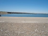 a view from the side of a concrete area near some water and the sky in the background