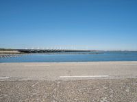 a view from the side of a concrete area near some water and the sky in the background