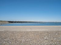 a view from the side of a concrete area near some water and the sky in the background