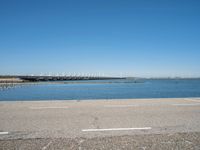 a view from the side of a concrete area near some water and the sky in the background