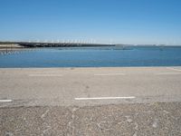 a view from the side of a concrete area near some water and the sky in the background