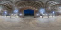 the 360 - lens shot shows a large horse arena with wooden floors and lights on