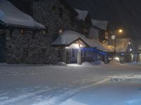 a large group of snow covered buildings in the street at night on a snowy day