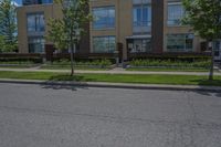 a large brick building on a street with a few trees and grass in front of it