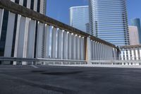 a person skate boarding on a bridge and surrounded by tall buildings and other high rise office towers