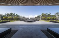 a large fountain with a bench and plants in it sitting in a large open space