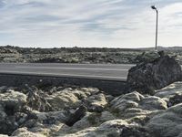 a street light on top of the rocks next to the road on a sunny day