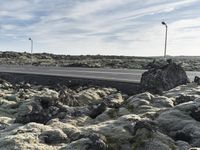 a street light on top of the rocks next to the road on a sunny day