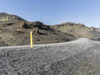 a road sign on the side of the road in front of a rocky slope covered in black granite