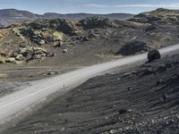 a motorcycle is on the dirt road near the rocks and mountains in a barren place