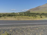 a large grassy landscape along side a small street, including the edge of a highway