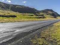 a view of some hills and road in iceland, near a sign on the side