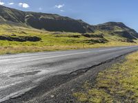 a view of some hills and road in iceland, near a sign on the side