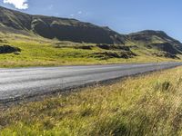 a view of some hills and road in iceland, near a sign on the side