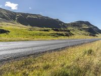 a view of some hills and road in iceland, near a sign on the side