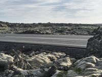 a car is on the road and parked near rocks in the desert with a gravel highway