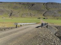 a large dirt road next to a hill with a long train coming out of it