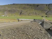 a large dirt road next to a hill with a long train coming out of it