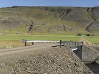 a large dirt road next to a hill with a long train coming out of it