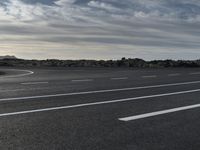 a lone car on a empty open road on a windy day in the desert on a cloudy day