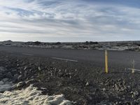 a long road on a barren terrain with lots of rocks and grass on both sides