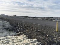 a long road on a barren terrain with lots of rocks and grass on both sides