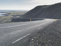 an empty road with a couple cars on it at the side of it and some hills