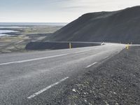 an empty road with a couple cars on it at the side of it and some hills