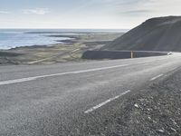 an empty road with a couple cars on it at the side of it and some hills