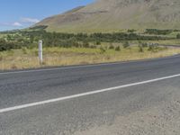 a empty road and a car on the side of the road with a mountain in the distance