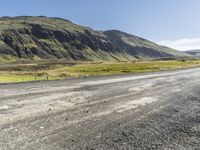 a motorcycle parked on top of a gravel road under a blue sky in a valley