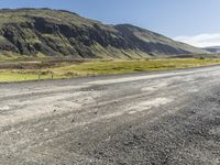 a motorcycle parked on top of a gravel road under a blue sky in a valley