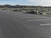 there is a parking lot on the side of a hill with some rocks surrounding it