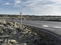 a road with a white arrow painted on it next to rocks and grass in the desert