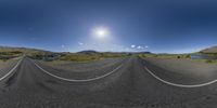 this is a panorama of the road with mountains in the background and two white lines in the middle