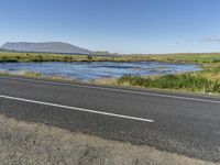 the tarmac and road are lined with shallow water on the far bank, overlooking a mountainous lake