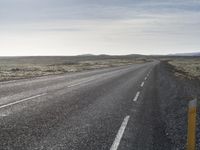 an empty road and a yellow sign sitting on the side of it's lane