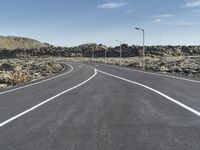 a deserted road in the middle of the desert at dusk with two lane markings on both sides